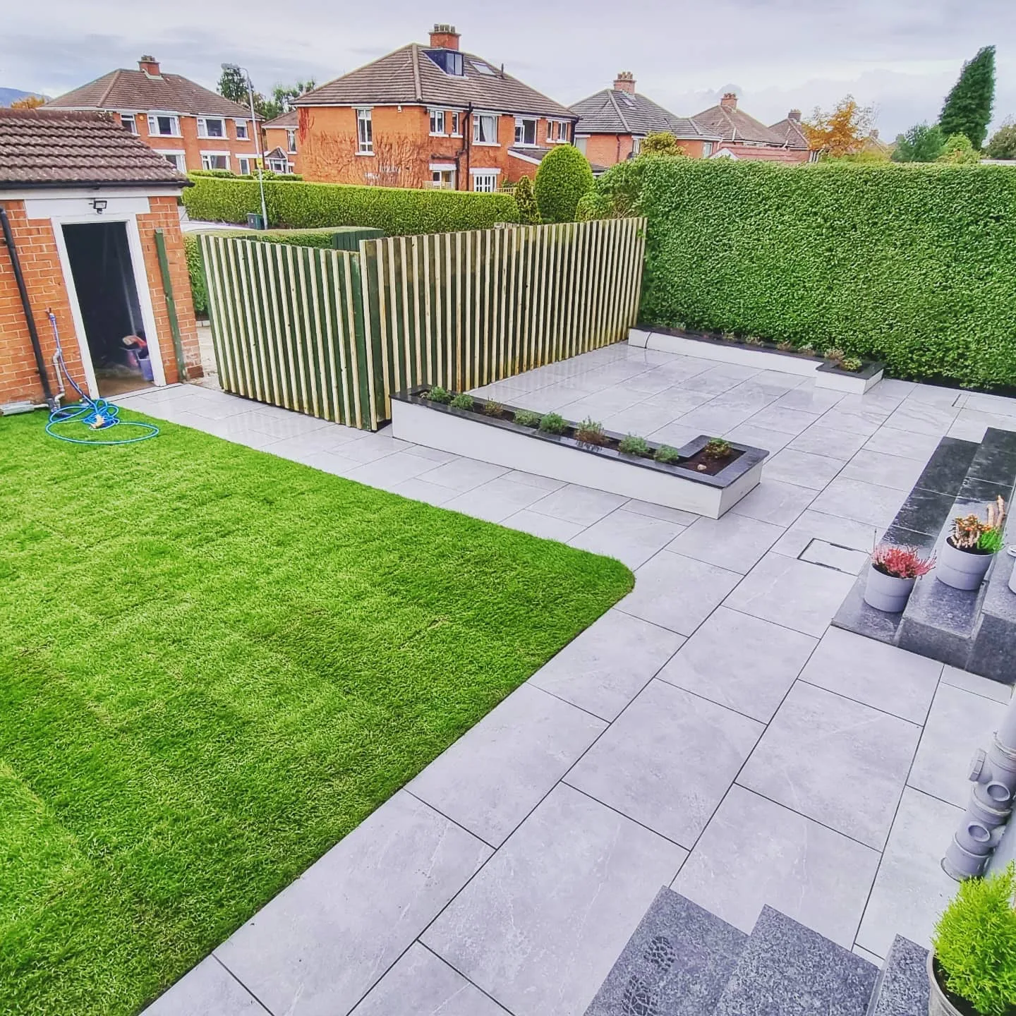 Back garden with paving, lawn and timber fencing
